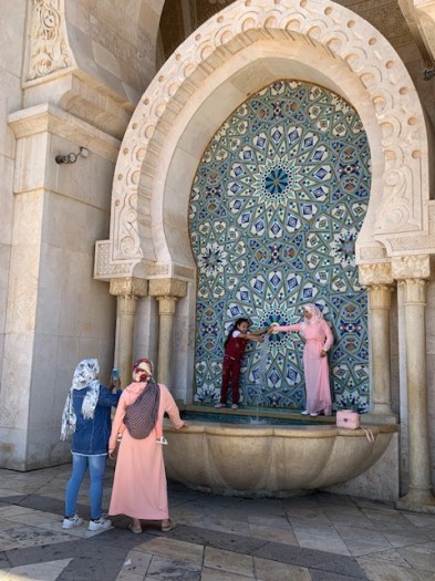 A muslim family having fun at an outdoor ablution fountain.