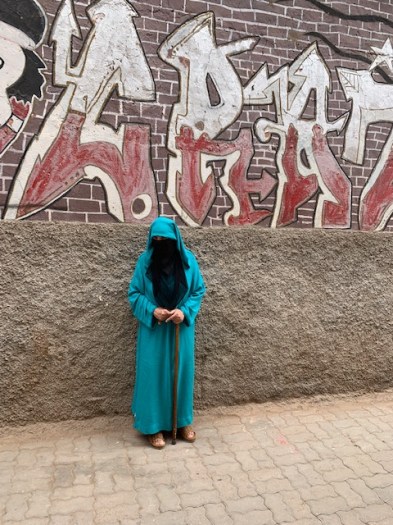 A local lady under a large graffitii.