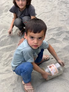 Kids playing in the sand along the path next to the ditch.
